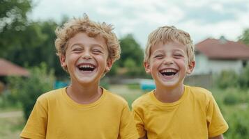 Joyful children laughing together in matching yellow shirts outdoors photo