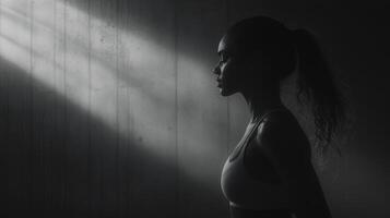 girl in sports top stands in shadows, illuminated by soft light photo