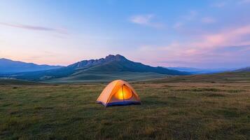 bright orange tent stands in serene mountain landscape at dusk photo