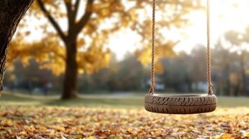 nostalgic scene of old tire swing hanging from tree in autumn photo