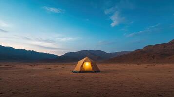 serene desert camp at dusk with glowing tent and mountains photo