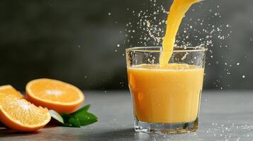 Fresh orange juice being poured into glass, with splashes and oranges nearby photo