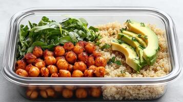 Healthy meal prep container with quinoa, chickpeas, avocado, and greens photo