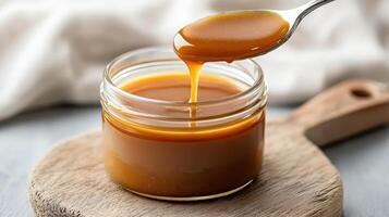 Thick caramel sauce drips from spoon, showcasing its rich texture and glossy finish photo
