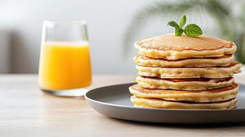 Delicious pancakes stacked high on plate, accompanied by refreshing glass of orange juice photo