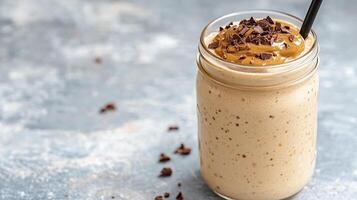 Creamy smoothie in glass jar topped with chocolate and peanut butter, perfect for healthy treat photo