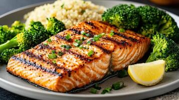 Grilled salmon with steamed broccoli and quinoa on plate, showcasing healthy meal photo
