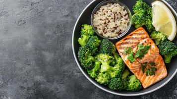 Grilled salmon with steamed broccoli and quinoa, garnished with lemon, offers healthy meal photo