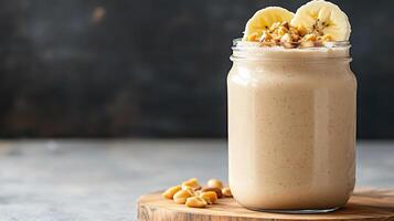 Creamy peanut butter protein shake topped with banana slices and nuts, served in mason jar photo