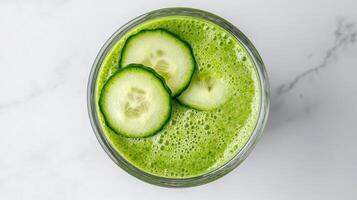 Fresh green juice with cucumber slices on top, showcasing vibrant color and healthy ingredients photo