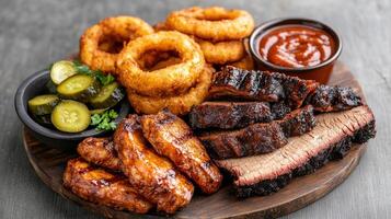 Delicious barbecue meal featuring smoked ribs, brisket, onion rings, and pickles photo
