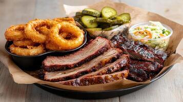 Delicious barbecue meal featuring smoked brisket, onion rings, pickles, and coleslaw photo
