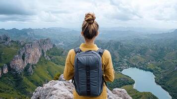 young adventurer stands rocky peak, gazing breathtaking mountain landscape and serene lake below photo