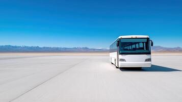 white shuttle bus parked on vast, empty under clear blue sky, surrounded by mountains photo