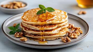Fluffy pancakes stacked high, drizzled with syrup, and garnished with mint and walnuts photo
