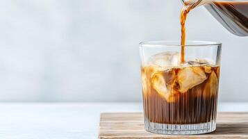 refreshing cold brew coffee is being poured over ice in glass, creating delightful visual photo