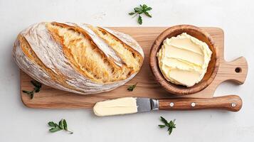 Freshly baked bread with creamy butter on wooden board photo