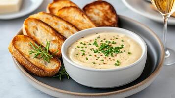 Creamy cheese dip served with crispy toasted bread slices, garnished with herbs photo