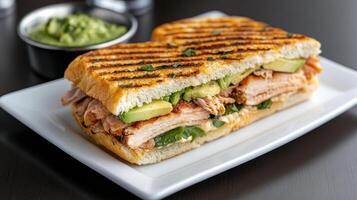 Gourmet Cuban sandwich with smoked turkey, avocado, and fresh greens, served with side of photo