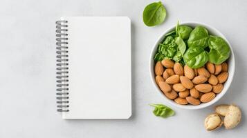 clean notebook beside bowl of fresh spinach and almonds, perfect for meal planning photo