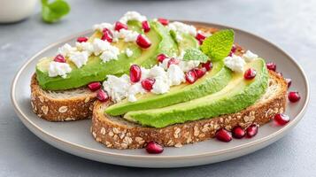 Creamy avocado toast topped with pomegranate seeds and fresh mint on whole grain bread photo