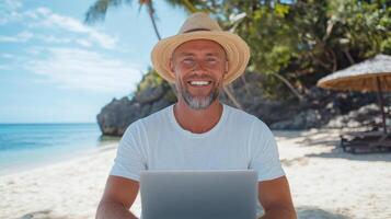man with straw hat smiles while working on laptop at beach, enjoying sunny day photo