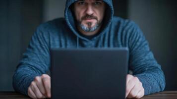 focused individual in hoodie is intently using laptop, creating sense of mystery and intrigue photo