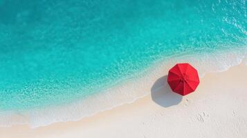 vibrant red umbrella stands sandy beach beside clear turquoise water, creating serene atmosphere photo
