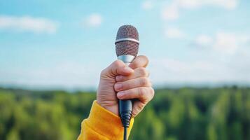 hand holding microphone against scenic outdoor background, symbolizing performance and photo