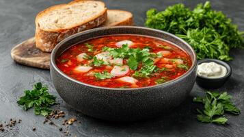 steaming bowl of vibrant soup garnished with fresh herbs, served with bread photo