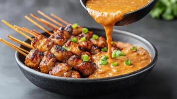 steaming bowl of spicy sauce poured over grilled skewers, creating delicious meal photo