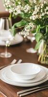 Elegant dining table set with white dinnerware and blooming flowers, creating a sophisticated ambiance photo