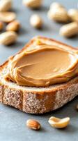 Delicious creamy peanut butter spread on fresh slice of bread with peanuts in warm rustic kitchen setting photo