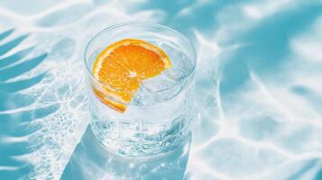 Refreshing citrus beverage in transparent glass with ice over sunlit pool water reflections photo