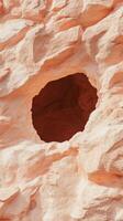 Natural erosion creates a unique cave formation in a sandy red rock cliff face, highlighted by sunlight photo