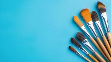 Assorted paintbrushes arranged on blue canvas ready for artistic expression and creative projects photo