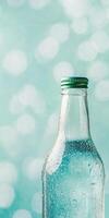 Refreshing glass bottle with water droplets and blue bokeh background photo