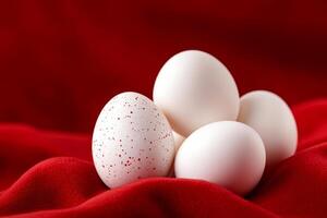 Speckled and plain eggs on a rich red fabric background evoking elegance and simplicity in still life composition photo