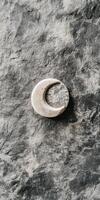 Rustic crescent moon shaped stone on textured dark gray surface photo