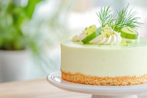 Delicious lime cheesecake garnished with fresh dill and lime slices on a cake stand in a bright kitchen setting photo