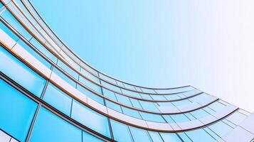 Modern glass building facade reflecting clear blue sky with curved architectural design photo