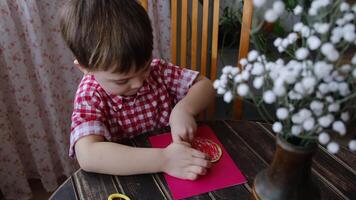 Making DIY gift for Mothers day or Valentines day. Small boy attach heart to DIY greeting card using plasticine. video