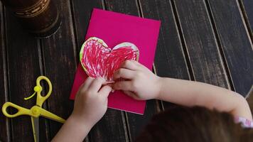 Making DIY gift for Mothers day or Valentines day. Small child attach heart to DIY greeting card using plasticine. video