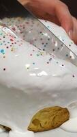 Traditional Easter cake with cut piece and colored eggs on light table. Candle flame flickers from the draft. video