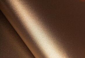 Warm gold and bronze paper background with a glossy, pearlescent texture and shimmering glitter photo