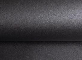 Elegant black paper texture with a shimmering, glittering finish and curved, rolled edges. Luxurious photo