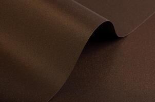 Warm brown paper background with a smooth, grainy texture and metallic bronze shimmer. A subtle photo