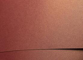 Burgundy paper background with a glossy, pearlescent texture and shimmering metallic finish. Rich, photo
