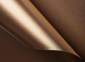 Gold and bronze paper background with a pearlescent, glossy texture and shimmering reflective photo