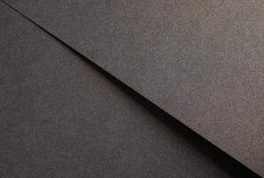 Elegant black paper texture with a shimmering golden sparkle and grainy finish. Luxurious designer photo